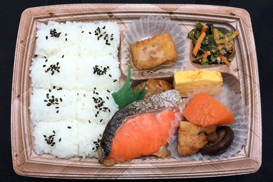 Japanese bento box with grilled salmon, tamagoyaki, rice with black sesame, simmered vegetables and spinach